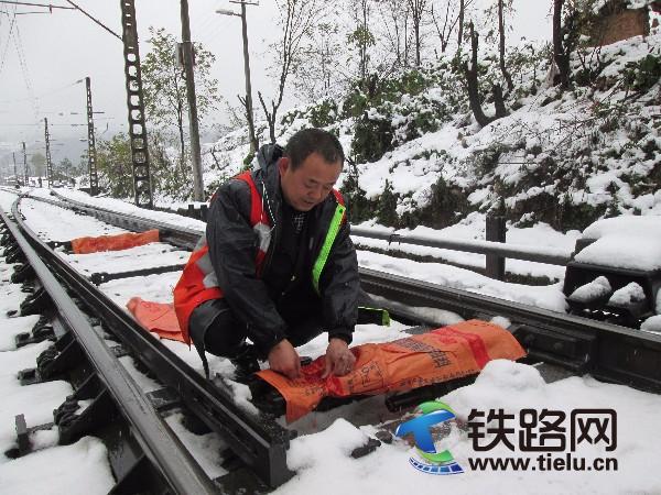 图为：该段乐武车站副站长张洪平正在用塑料袋捆绑道岔连接杆，确保设备运转情况良好。.jpg